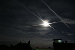 Fast-Vollmond hinter Flugzeugspuren