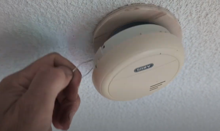 Der Trick mit der Drahtschlaufe: So lässt sich der Rauchmelder mit einem langen Stock bequem vom Boden aus von der Decke holen. 