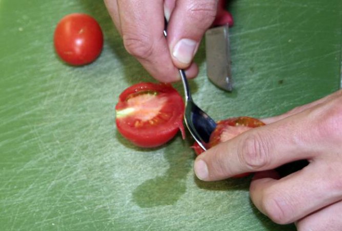Mit einem Löffel das glibbrige Tomatenmark samt Kernen heraustrennen
